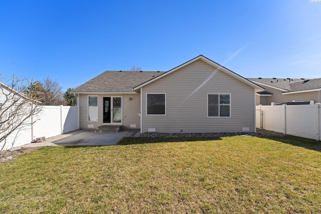 back of property with a patio, a fenced backyard, a shingled roof, crawl space, and a lawn