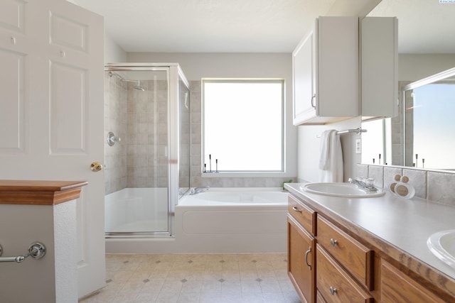 full bath with a stall shower, a garden tub, a sink, and double vanity