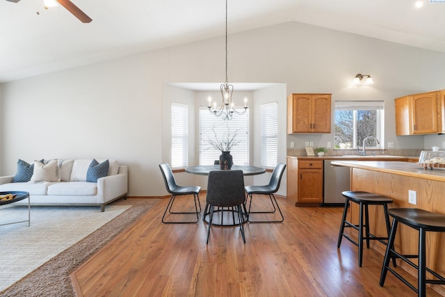 kitchen with lofted ceiling, ceiling fan with notable chandelier, dishwasher, light wood finished floors, and pendant lighting