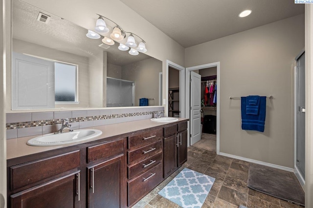 full bathroom with baseboards, a shower stall, visible vents, and a sink