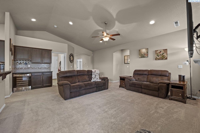 living room with wine cooler, arched walkways, visible vents, light carpet, and vaulted ceiling