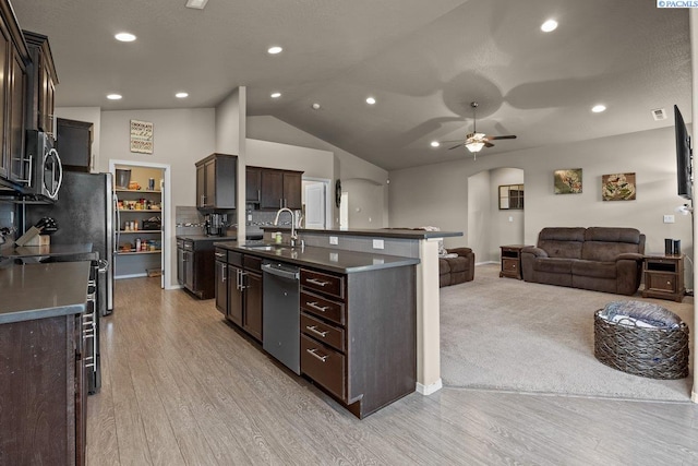 kitchen with dark countertops, arched walkways, open floor plan, and a sink