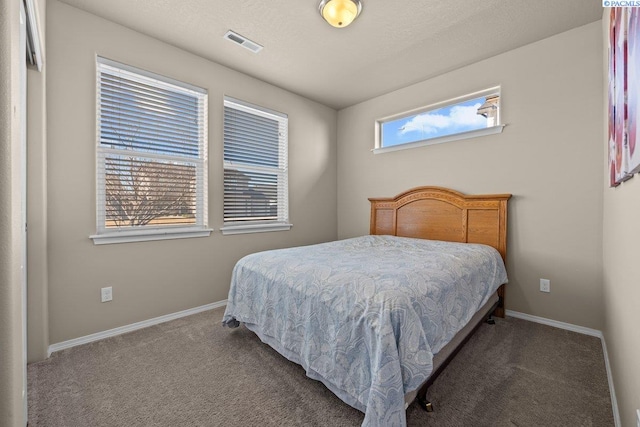 bedroom featuring a textured ceiling, carpet, visible vents, and baseboards