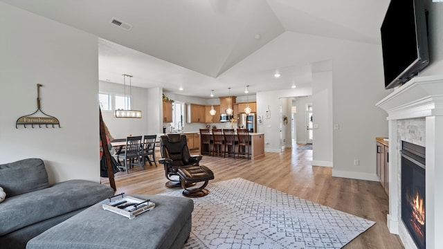 6012 W 31st Ave, Kennewick, WA 99336 - living area with light wood-style flooring, a glass covered fireplace, lofted ceiling, a chandelier, and baseboards