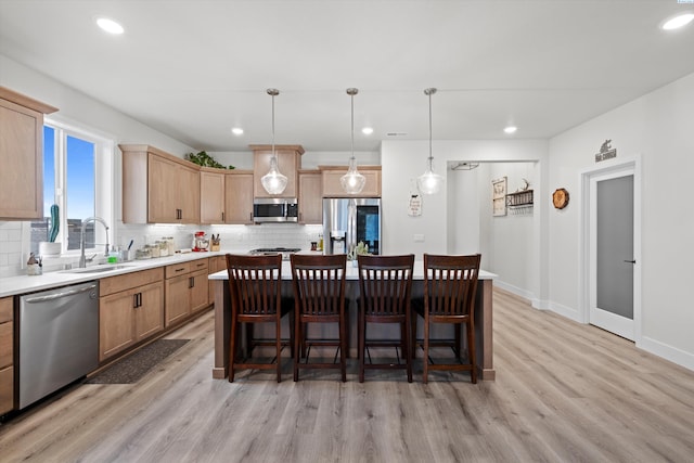 kitchen with appliances with stainless steel finishes, a sink, backsplash, light wood finished floors, and recessed lighting