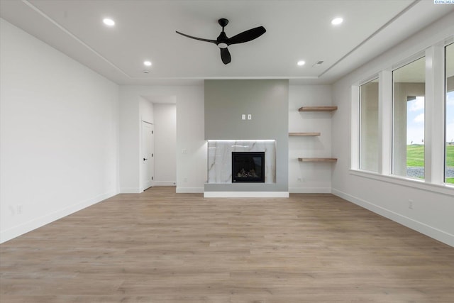 unfurnished living room featuring a fireplace, light hardwood / wood-style flooring, and ceiling fan