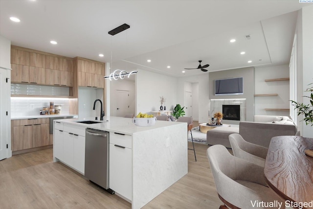 kitchen with sink, stainless steel dishwasher, pendant lighting, a kitchen island with sink, and white cabinets