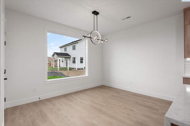 unfurnished dining area with a notable chandelier and light hardwood / wood-style floors