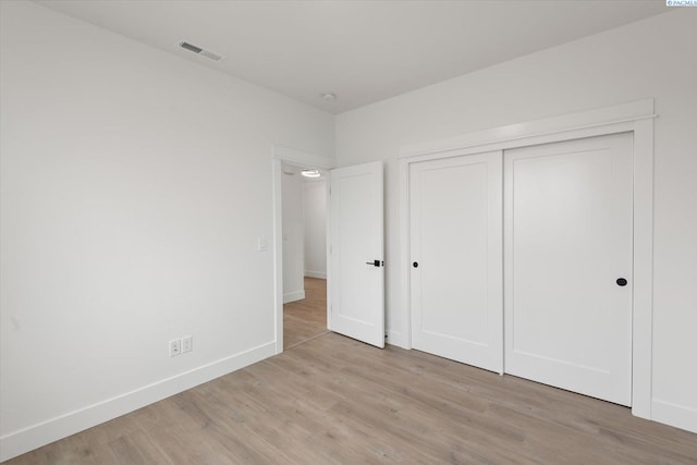 unfurnished bedroom with light wood-type flooring and a closet