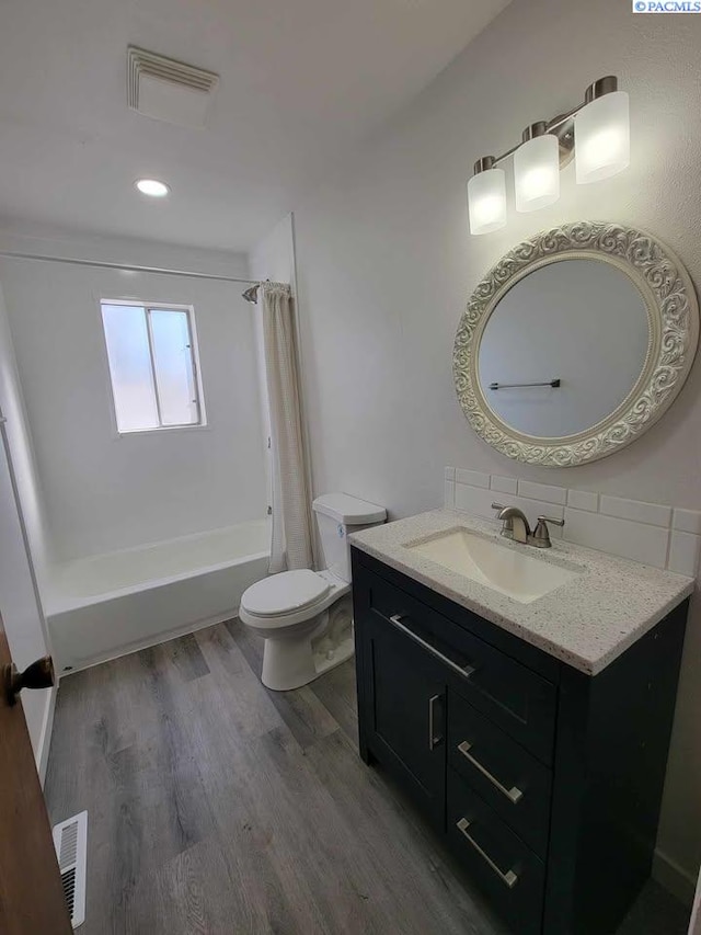 full bath featuring toilet, wood finished floors, vanity, visible vents, and shower / bath combo with shower curtain