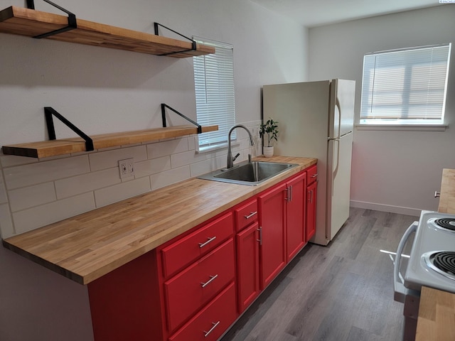 208 E 4th St, Grandview, WA 98930 - kitchen featuring a sink, butcher block counters, red cabinets, and wood finished floors