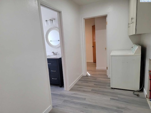 laundry room with baseboards, light wood-style flooring, washer / clothes dryer, and a sink