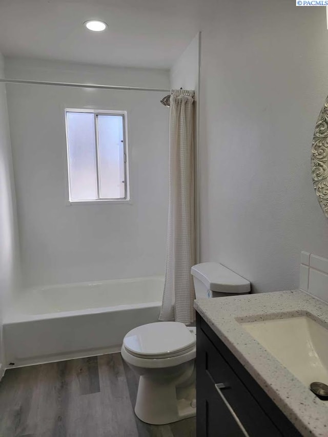 bathroom featuring toilet, vanity, wood finished floors, and shower / tub combo with curtain