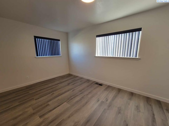 unfurnished room with baseboards, visible vents, and wood finished floors