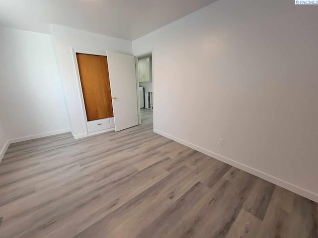 empty room with light wood-style flooring and baseboards