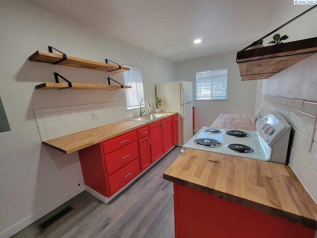 kitchen with white appliances, visible vents, wooden counters, and a sink