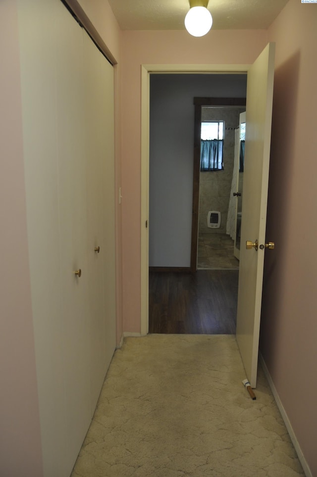 corridor featuring baseboards and carpet flooring