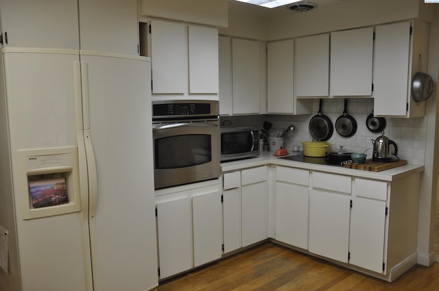kitchen featuring white cabinets, light countertops, stainless steel appliances, decorative backsplash, and wood finished floors