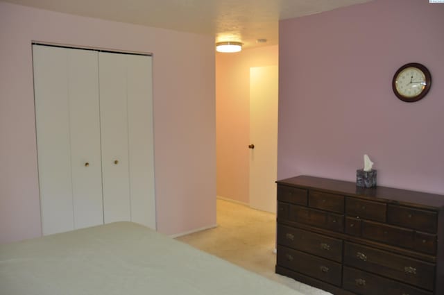 bedroom with baseboards, light carpet, and a closet