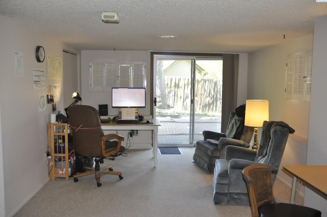 office area with a textured ceiling, baseboards, and carpet