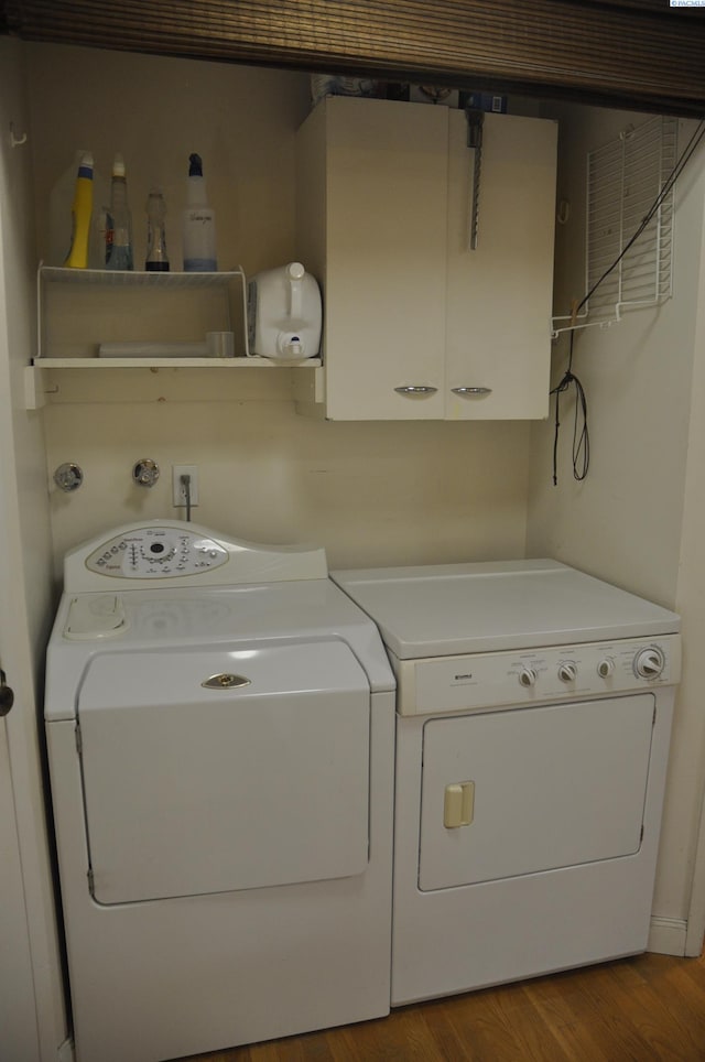 washroom featuring wood finished floors, cabinet space, and washer and clothes dryer