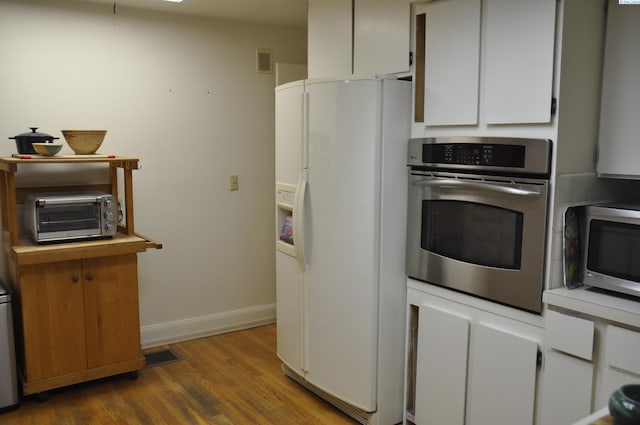 kitchen featuring visible vents, wood finished floors, a toaster, baseboards, and stainless steel appliances