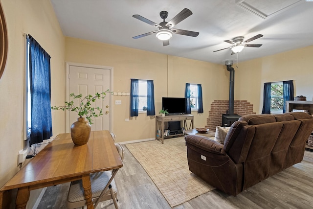 living room featuring ceiling fan, light hardwood / wood-style floors, and a wood stove