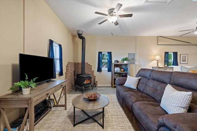 living room featuring plenty of natural light, a wood stove, electric panel, and ceiling fan