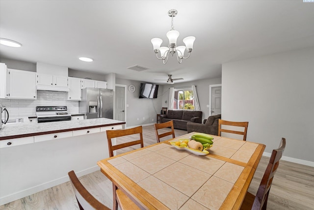 dining space featuring ceiling fan with notable chandelier and light hardwood / wood-style flooring