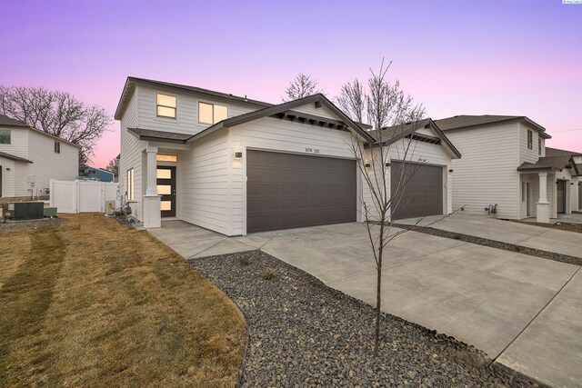 view of front of home featuring a garage, a lawn, and central air condition unit