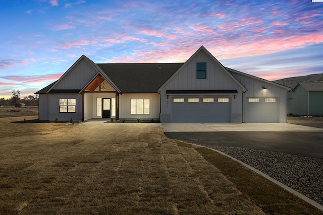 modern inspired farmhouse featuring an attached garage, a yard, board and batten siding, and concrete driveway