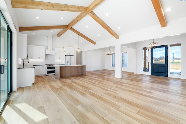 kitchen featuring a kitchen island, high quality appliances, open floor plan, wall chimney range hood, and an inviting chandelier