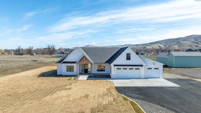 modern inspired farmhouse featuring driveway, an attached garage, a mountain view, board and batten siding, and a front yard