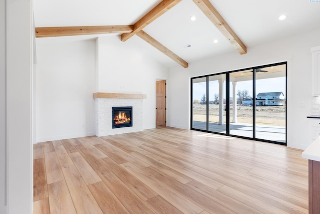 unfurnished living room featuring recessed lighting, light wood-style flooring, lofted ceiling with beams, a brick fireplace, and baseboards