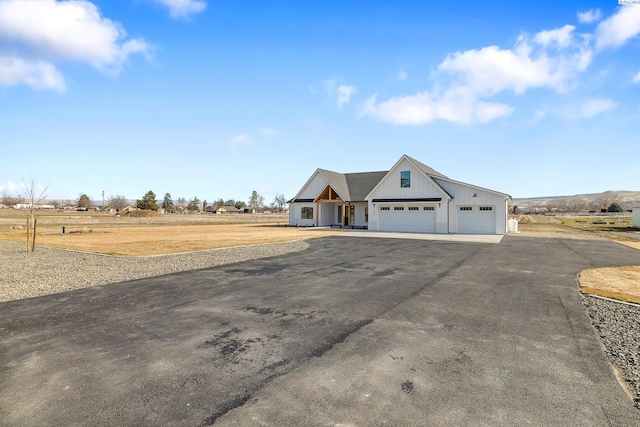 view of front of home with an attached garage, aphalt driveway, and board and batten siding