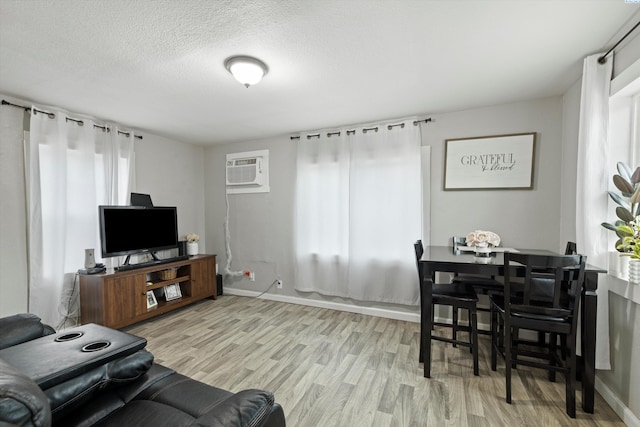 living room featuring a textured ceiling, light hardwood / wood-style floors, and a wall mounted AC