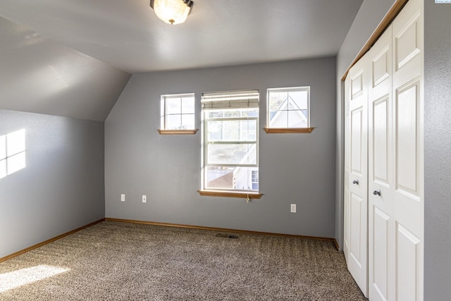 additional living space with carpet flooring, plenty of natural light, baseboards, and vaulted ceiling
