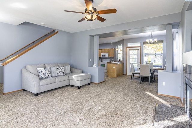 living area featuring light carpet, a ceiling fan, a chandelier, and baseboards