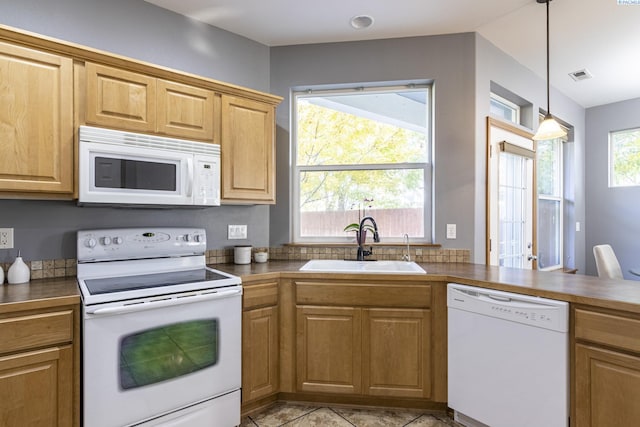 kitchen featuring white appliances, a sink, dark countertops, and hanging light fixtures