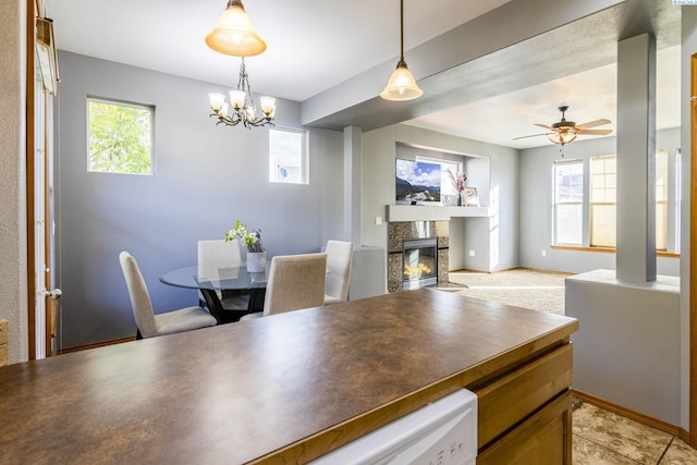 dining space with a glass covered fireplace, healthy amount of natural light, a chandelier, and a ceiling fan