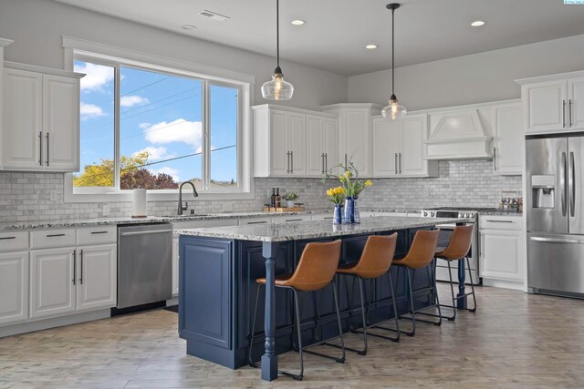 kitchen with appliances with stainless steel finishes, white cabinetry, custom exhaust hood, hanging light fixtures, and a center island