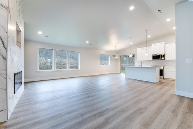 6150 W 30th Pl, Kennewick, WA 99338 - unfurnished living room featuring a fireplace, light wood-type flooring, vaulted ceiling, recessed lighting, and baseboards