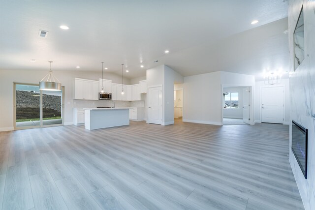 6150 W 30th Pl, Kennewick, WA 99338 - unfurnished living room with baseboards, plenty of natural light, recessed lighting, light wood-style flooring, and lofted ceiling