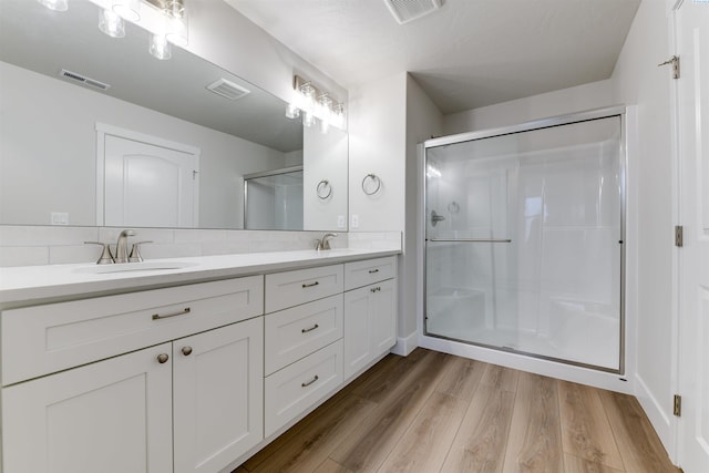 6150 W 30th Pl, Kennewick, WA 99338 - bathroom featuring a stall shower, wood finished floors, double vanity, and tasteful backsplash
