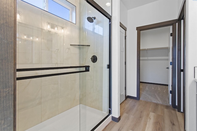 bathroom with a shower with shower door and hardwood / wood-style floors