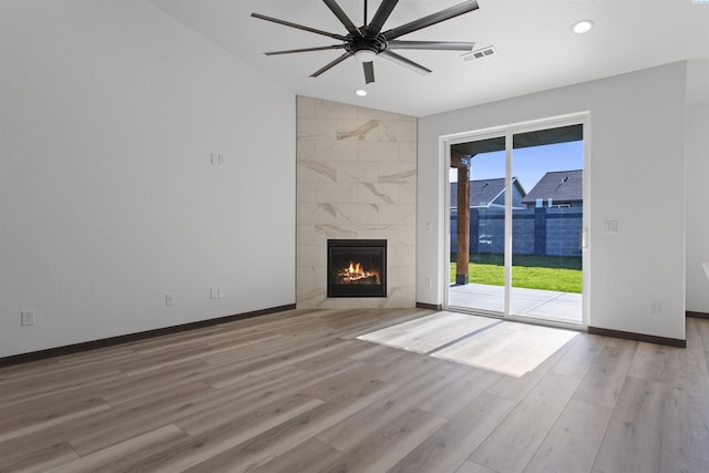 unfurnished living room with ceiling fan, a high end fireplace, and light hardwood / wood-style flooring