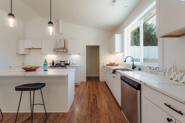 kitchen with pendant lighting, sink, white cabinetry, stainless steel appliances, and wall chimney exhaust hood