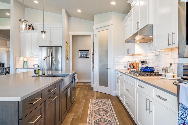kitchen with under cabinet range hood, stainless steel appliances, a sink, light countertops, and recessed lighting