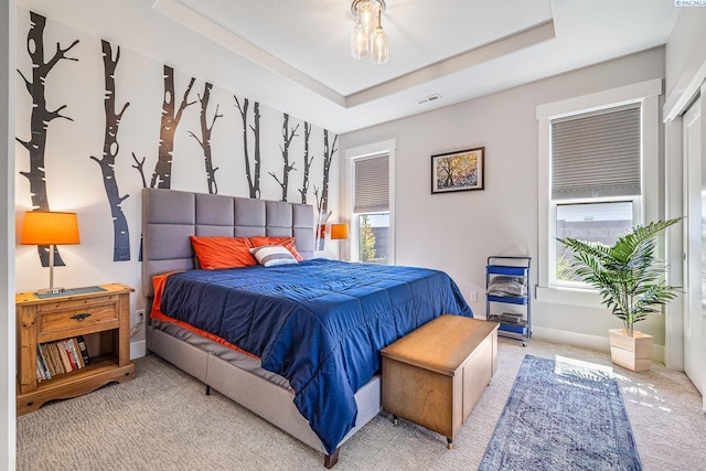 bedroom with carpet flooring, multiple windows, a tray ceiling, and baseboards