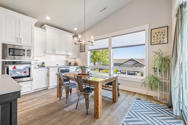 dining room with a chandelier, beverage cooler, light wood-type flooring, recessed lighting, and high vaulted ceiling